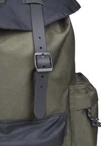 Sac à dos en tissu vert avec un rabat supérieur bleu foncé, une sangle noire réglable avec une boucle en métal, et une poche latérale avec un cordon de serrage.