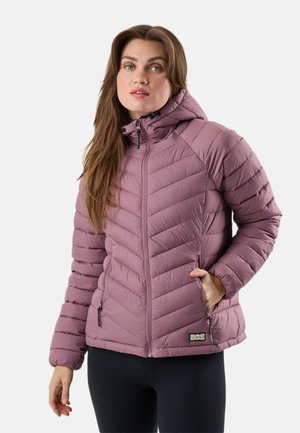 Vrouw draagt een mauve gewatteerde jas met capuchon en ritssluiting aan de voorkant, samen met zwarte legging, staand tegen een witte achtergrond.