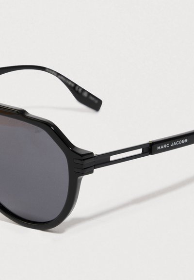 Occhiali da sole neri, di forma ottagonale, con lenti scure. La montatura in metallo presenta un design angolare, bracci testurizzati e un dettaglio con logo.