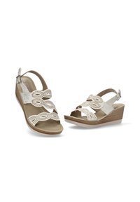 Sandalias de cuña beige con correas decorativas de corte, que presentan una suela texturizada y una hebilla ajustable en el tobillo para un ajuste seguro.