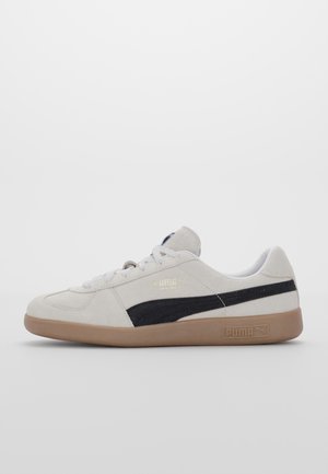 Sneakers Puma in suede grigio chiaro con una striscia nera. Presentano una suola in gomma, design con lacci e logo impresso sul lato.