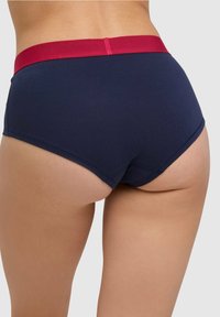 Granatowe bawełniane bokserki z szerokim bordowym paskiem w pasie. Charakteryzują się gładką teksturą i klasycznym krojem hipsterskim. Brak widocznych wzorów lub elementów metalowych.