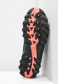 Czarna gumowa podeszwa z głębokim bieżnikiem; posiada różowy pasek akcentujący wzdłuż środka oraz ostre, kanciaste wzory bieżnika zapewniające przyczepność.