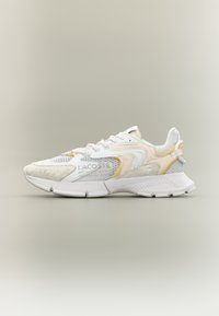 Baskets Lacoste avec une tige en mesh blanc, des accents jaunes et gris, des détails texturés et une semelle en caoutchouc au design contrastant.