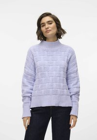 Ljus lavendelfärgad stickad tröja med ett strukturerat korgvävmönster, med hög krage och ribbade ärmslut, i kombination med mörka jeans.