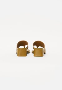 Tan leather block-heeled sandals with an open back and rounded cutouts, featuring a smooth finish and minimalist design.