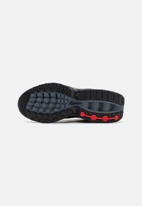 Sole di scarpa Nike nera e grigia con battistrada testurizzato, capsule di ammortizzazione blu e accenti circolari rossi su sfondo bianco.