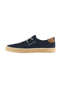 Tumes sinised kanva sneakers, millel on tekstuuriga jute põhi, pruun nahast aktsent kanna juures ja beežid lipsud. Brändi logo on külgedel välja pandud.