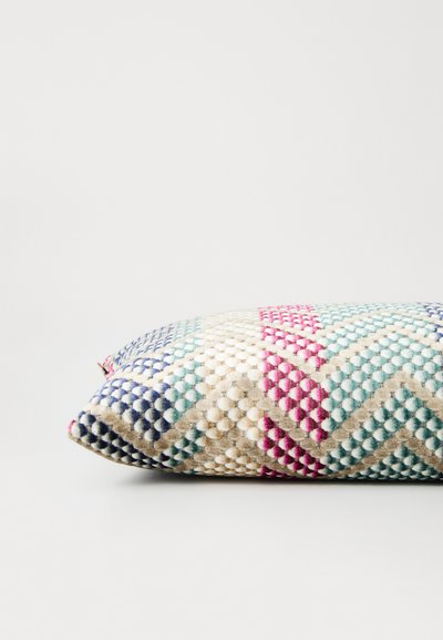 Textured rectangular throw pillow featuring a zigzag pattern in cream, blue, pink, and green on a beige background.