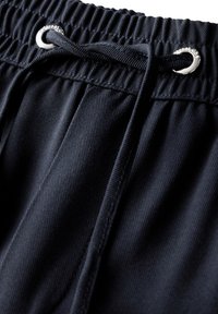 Sorte atletiske shorts lavet af glat materiale, med elastisk talje, øjer og snor. Synlige syninger.