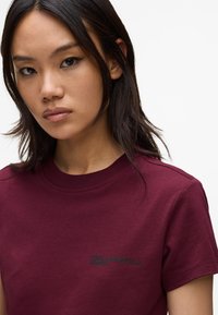 Tricou din bumbac burgund cu guler rotund și mâneci scurte. Prezintă textul brodat negru "Karl Lagerfeld Jeans" pe piept.