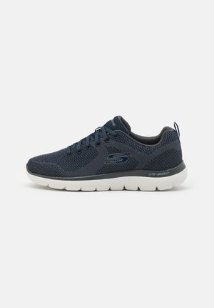 Zapatilla deportiva de color azul marino con parte superior de malla, ligera, con cuello acolchado y suela blanca con agarre. Presenta un sistema de cordones y detalle de logo.