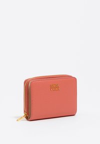 Cartera de cuero color coral con un acabado texturizado. Presenta un cierre de cremallera en tono dorado y el logo de la marca. Forma rectangular compacta con un interior liso.