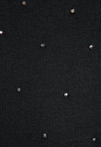 Czarna dzianina o teksturowanym wzorze, z rozrzuconymi metalicznymi ozdobami w odcieniach srebra i ciemnych barwach.