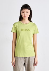 Short-sleeve, crew neck T-shirt in light green cotton, featuring a large "BOSS" print in a matching shade across the chest.