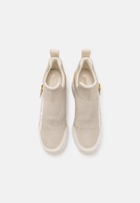 Beżowe wsuwane trampki wykonane z dzianiny z teksturowanymi panelami z siateczki, białe podeszwy i złote akcenty. Wyposażone w pętelki do łatwego zakładania.
