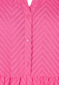 Růžové šaty s texturovaným vzorem chevron, s výstřihem do V a zapínáním na knoflíky. Tkanina vypadá měkká a lehká.