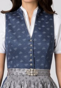 Blue floral-patterned vest with silver buttons, paired with a white blouse. Grey skirt with decorative belt featuring a metallic buckle.
