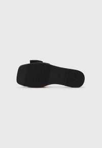 Talpa de pantof neagră, cu textură antiderapantă, având o formă lată și plată, cu margini netede. Fabricată din cauciuc, cu un design minimalist și fără elemente metalice vizibile.