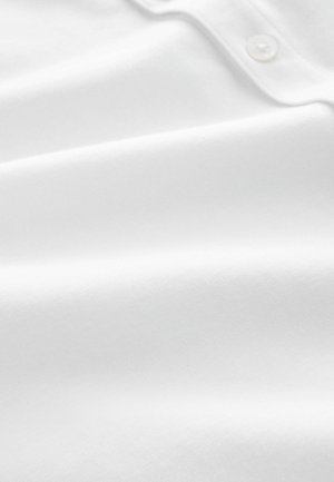 Weißer Baumwollstoff mit glatter Textur, der über einen Knopfdetails und ein dezentes eingewebtes Muster verfügt. Die Oberfläche wirkt weich und leicht reflektierend.