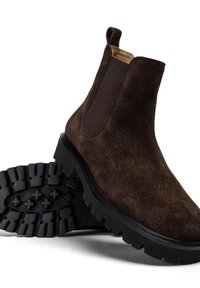 Stivaletti alla caviglia in suede marrone con pannelli laterali elasticizzati, una parte superiore imbottita e una suola in gomma nera con motivo di battistrada robusto.