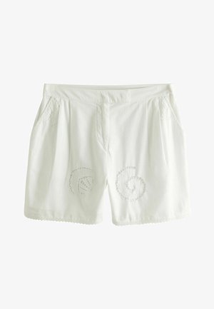 Hvide linnedshorts med broderede spiraldesigns på begge ben, plisseret front og små sidelommer med dekorativ blonderkant ved kanten.