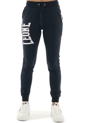 Modèle portant un pantalon de jogging noir Lonsdale avec un cordon de serrage à la taille et des baskets blanches.