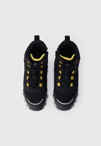 Ζευγάρι μαύρα και κίτρινα αθλητικά παπούτσια με ανακλαστικές λεπτομέρειες και ελαστικά κορδόνια με κωδικό, απεικονιζόμενα από πάνω σε λευκό φόντο.