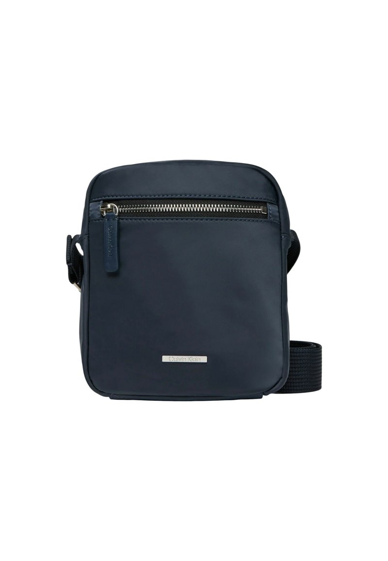 Borsa a tracolla blu navy in materiale resistente, con tasca frontale con zip, tracolla regolabile e una piccola placca con logo sul davanti.