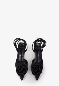 Scarpe con tacco alto nere con punte affusolate, materiale in satin, rosa decorativa in tessuto sulla punta e cinturini incrociati alla caviglia.