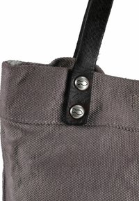 Grijze stoffen draagtas met een gestructureerd oppervlak, voorzien van een zwart leren hengsel en zilveren knoopaccenten in de vorm van vissen.