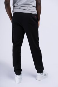 Black sweatpants made of soft fabric, featuring an elastic waistband, cuffed ankles, and a back pocket with a logo detail.
