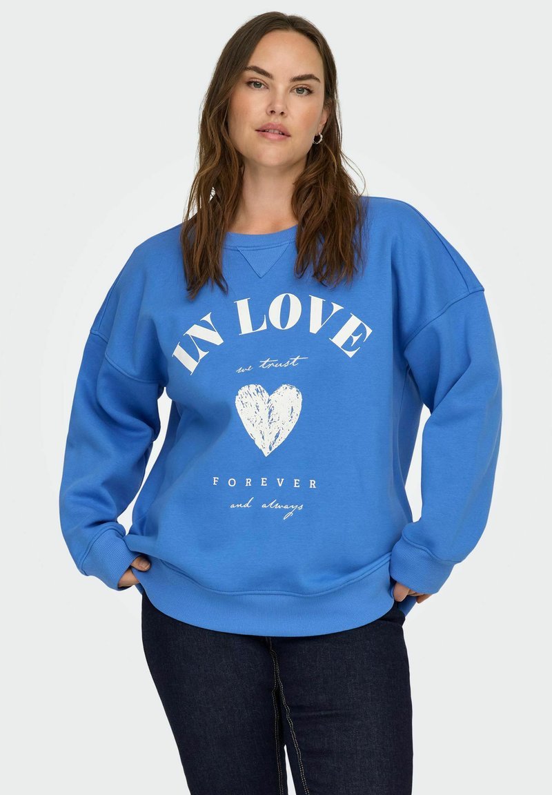 Sudadera azul de tejido suave, con un corte holgado, puños de canalé y texto impreso en blanco con un diseño de corazón en la parte delantera.