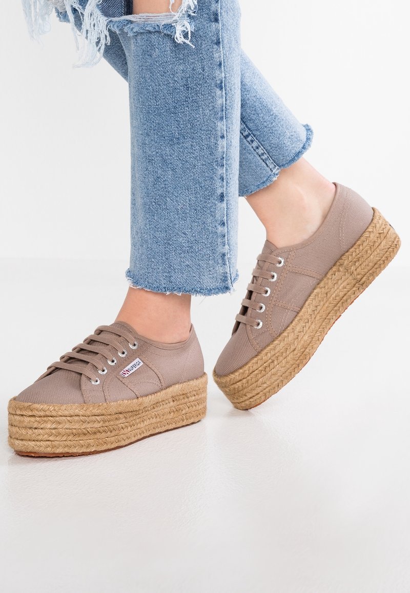 Tan-färgade canvasplattformssneakers med jute-rep-sulor, silverfärgade öglor och snören, parat med slitna ljusblå jeans.