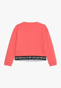 Sudadera de manga larga color coral con cuello de canalé y ribete negro elástico, que presenta el logo blanco de Emporio Armani y el emblema del águila repetidos.