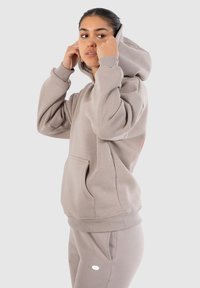 Sweat �à capuche gris avec une poche kangourou et des poignets côtelés. Fabriqué dans un matériau doux, avec un logo en bas à droite et une capuche doublée.