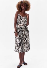 Beżowo-czarny zestaw składający się z krótki topu w zebrę i midi spódnicy, z guzikami i paskiem w talii, uszyty z lekkiego materiału.