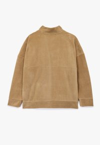 Beige, blød fleece-pullover med høj krave og lange ærmer. Har en glat tekstur og vandret sømdetaljer nær kanten.
