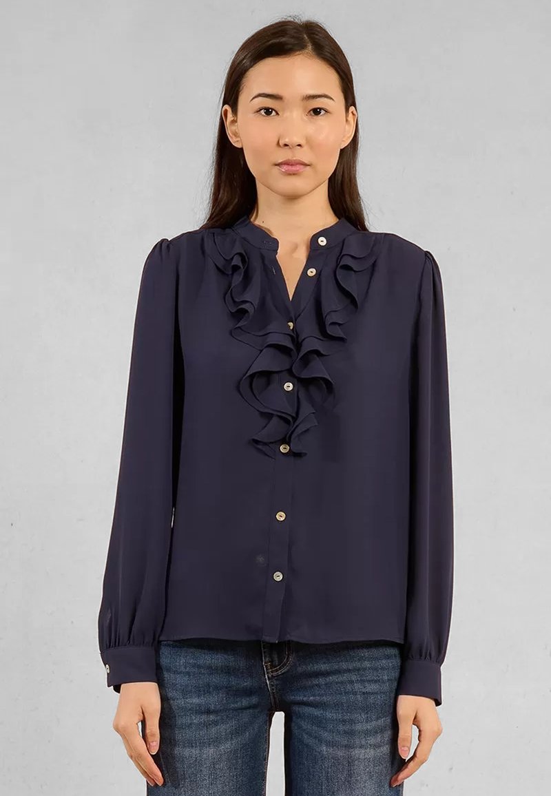 Blusa blu navy con frontale arruffato, colletto e maniche lunghe. Presenta bottoni dorati e un tessuto liscio e leggero.