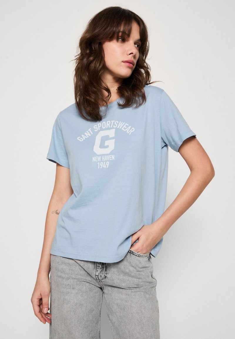 Ljusblå bomullströja med korta ärmar och rund hals. Har vit grafisk text "GANT SPORTSWEAR NEW HAVEN 1949" på framsidan.