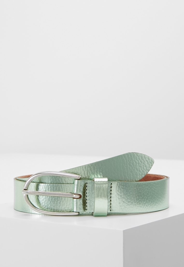 Ceinture en cuir texturé vert clair avec boucle argentée, enroulée sur une surface blanche sur un fond clair uni.