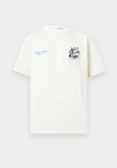 Λευκό κοντομάνικο μπλουζάκι με μπλε κείμενο «Filling Pieces Breaking Bread» και ένα μικρό σχέδιο με διαφορετικούς ανθρώπους να κάθονται γύρω από ένα τραπέζι.