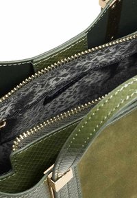 Groene handtas met een gladde buitenkant en textuuraccenten, voorzien van gouden hardware en een gestreepte zwarte voering met ritscompartimenten.