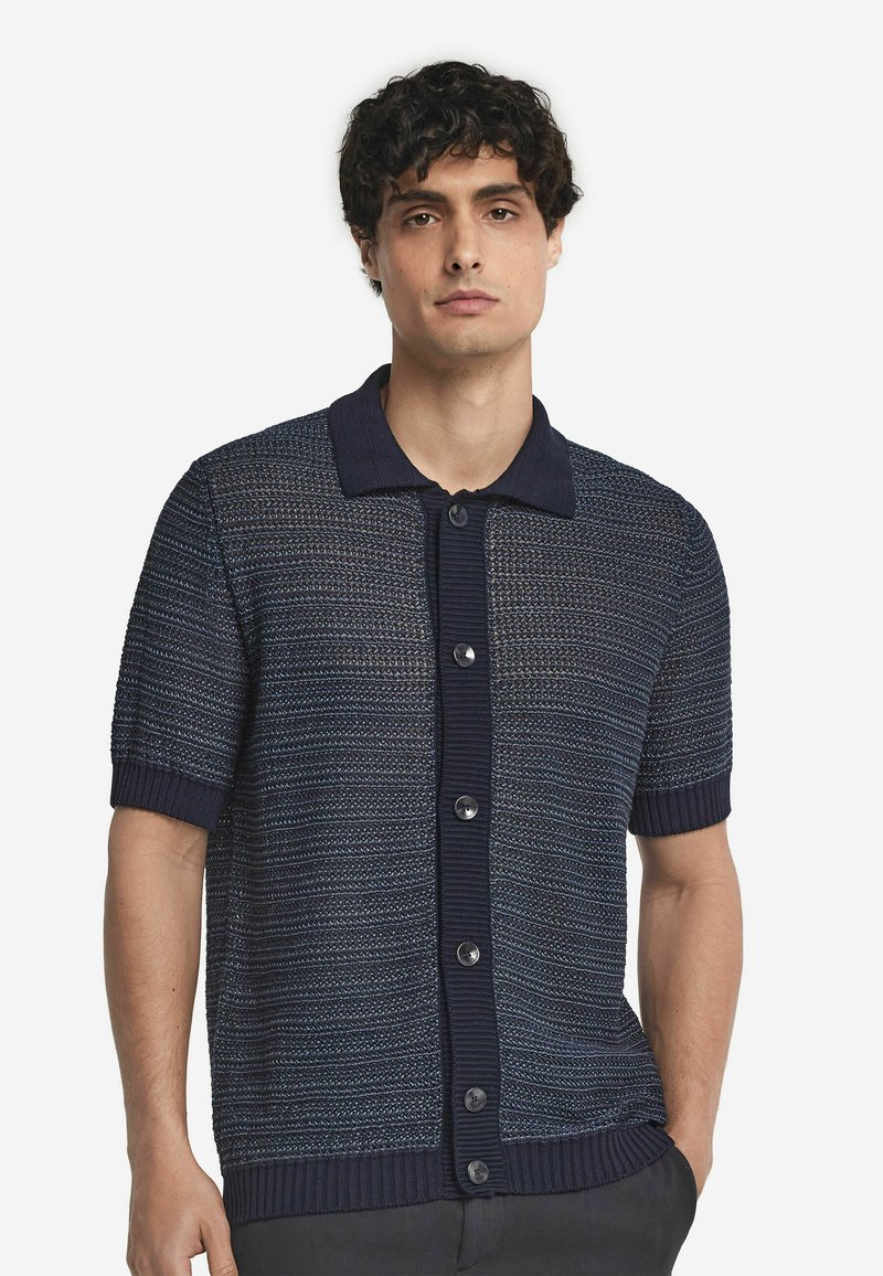 Marineblauwe kortekraag cardigan met een gestructureerd breiselontwerp, voorzien van een geribde kraag en knopen, geaccentueerd met lichte horizontale strepen.