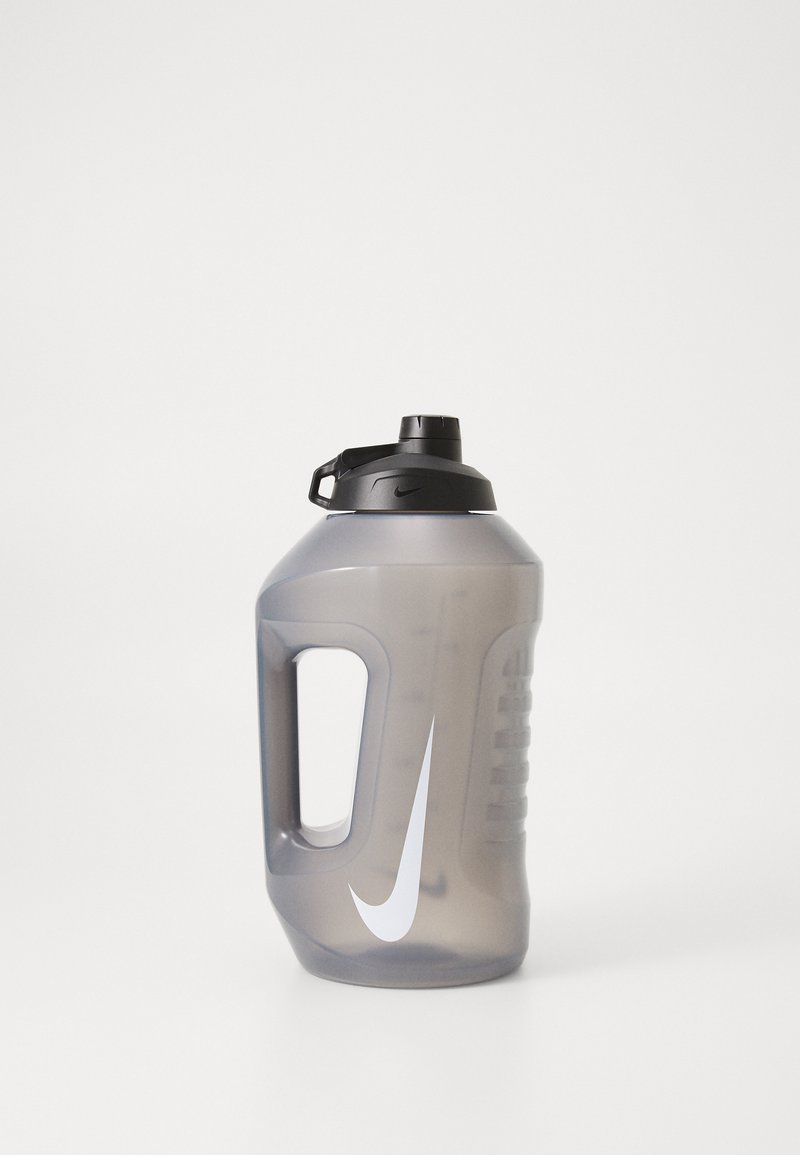 Nike vandflaske i gennemsigtigt gråt plast, med et sort skruelåg, sidehåndtag og hvid swoosh-logo. Ergonomisk design.