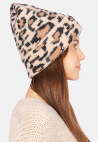 Bonnet en tricot à imprimé léopard dans des teintes beige, noir et tan. Texture douce, design relâché et détail de revers.