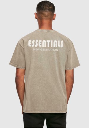 Beige bomulds t-shirt med korte ærmer, prydet med stor hvid tekst, der siger "ESSENTIALS NEW GENERATION" trykt på ryggen.