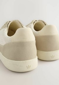 Zapatillas blancas y beige con parte superior de tejido texturizado, acentos de cuero suave, talón acolchado y suela de goma con un logo de corona.