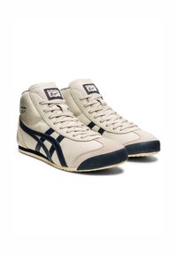 Beżowe sneakersy typu high-top z skórki z granatowymi akcentami, teksturowanym czubkiem i sznurówkami. Posiadają logo Onitsuka Tiger na języku.