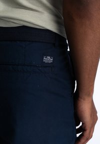 Shorts blu navy con una vita testurizzata, con un'etichetta applicata sulla tasca posteriore e dettagli di cucitura.